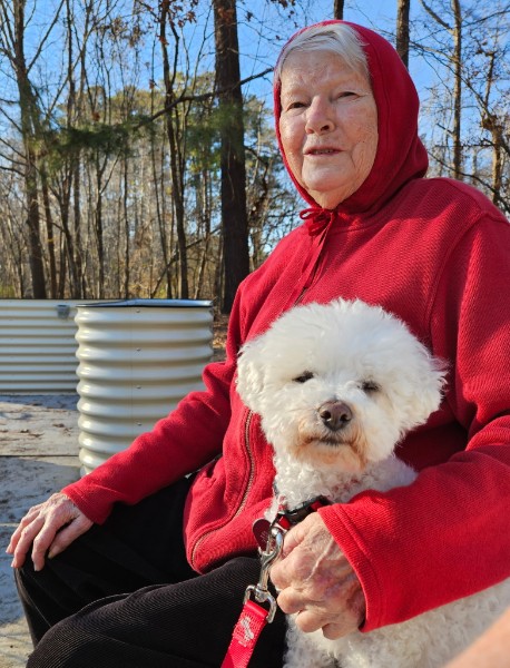Etta outdoors in red with her little white dog