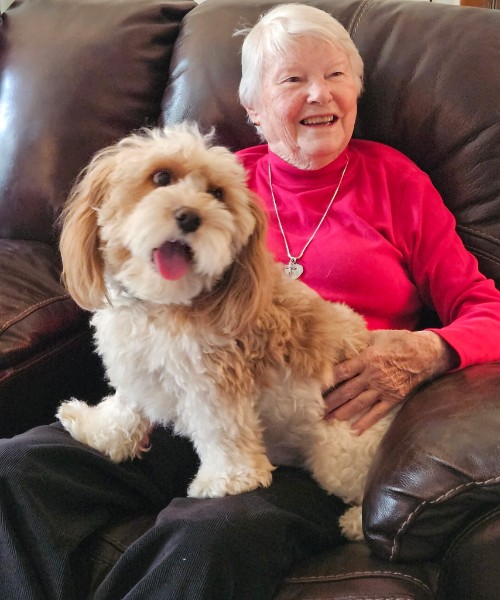 Etta smiling at home with her dog